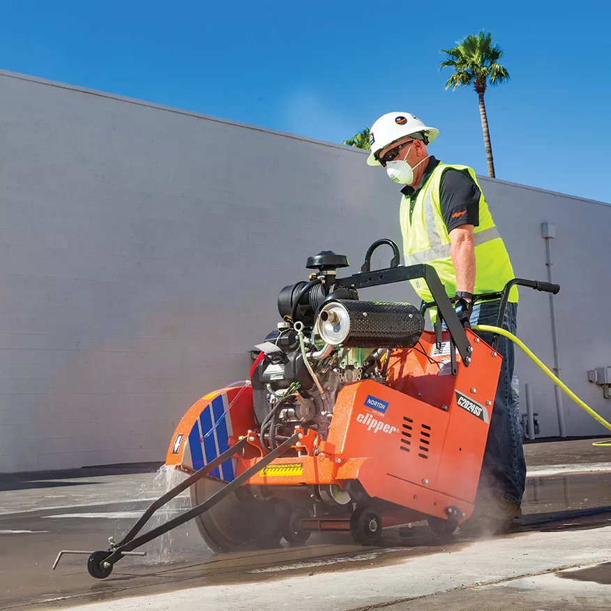 Worker cut-and-break sawing through a concrete wall