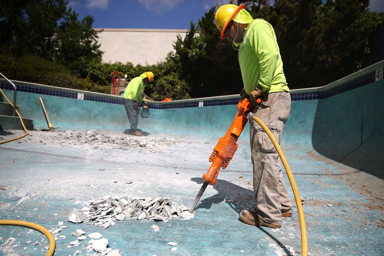 Crew demolishing a residential pool with jackhammers